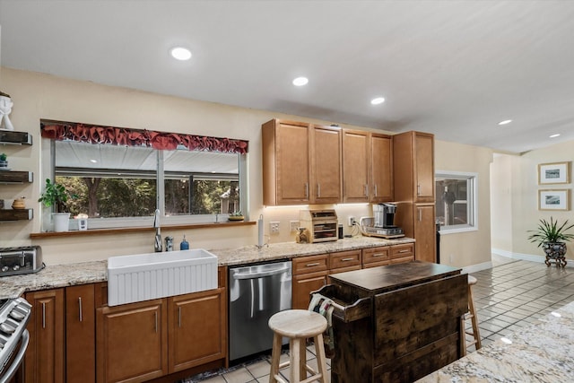 kitchen featuring sink, light tile patterned floors, stainless steel appliances, light stone countertops, and a healthy amount of sunlight