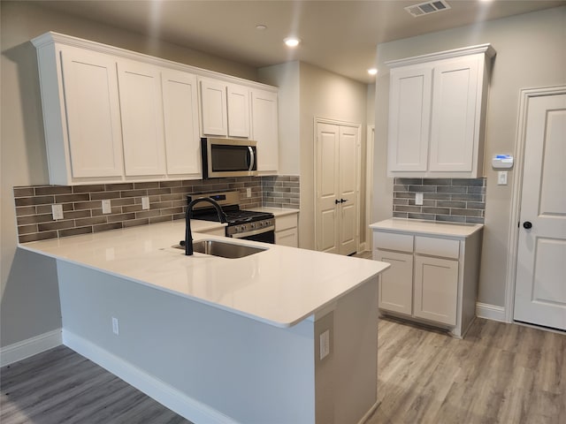 kitchen featuring white cabinetry, tasteful backsplash, light wood-type flooring, appliances with stainless steel finishes, and sink