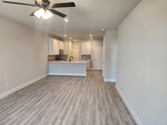 interior space featuring light hardwood / wood-style flooring, white cabinets, kitchen peninsula, backsplash, and ceiling fan