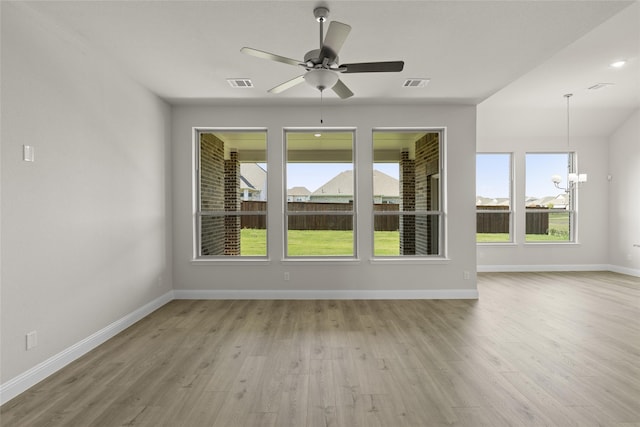 empty room with light hardwood / wood-style flooring and ceiling fan with notable chandelier