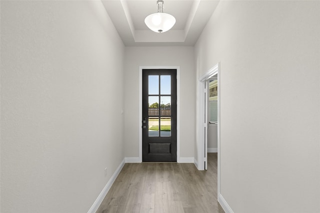 entryway with light hardwood / wood-style flooring and a tray ceiling