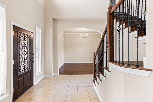 foyer entrance featuring crown molding, light hardwood / wood-style flooring, and an inviting chandelier