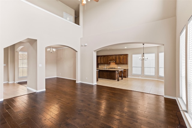 unfurnished living room featuring hardwood / wood-style flooring, an inviting chandelier, and a towering ceiling