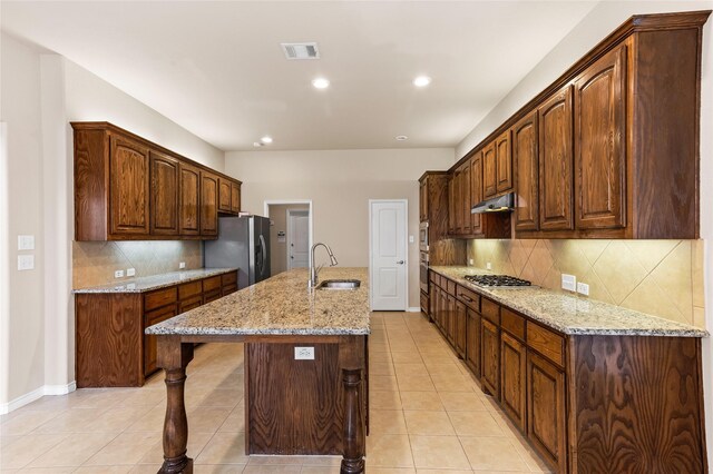 kitchen with a kitchen island with sink, appliances with stainless steel finishes, backsplash, and sink