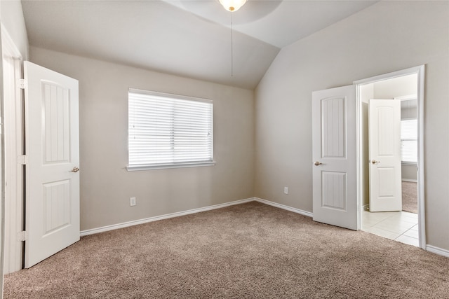 unfurnished bedroom featuring multiple windows, vaulted ceiling, and light colored carpet