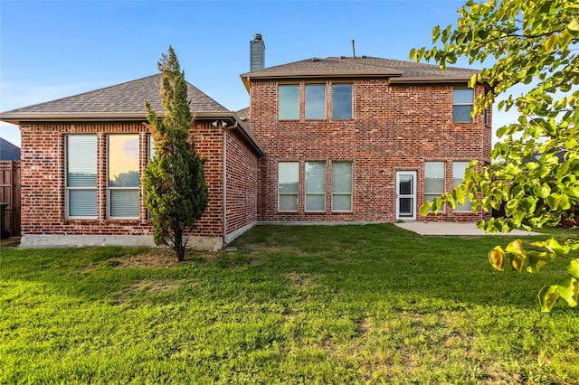 back of property with a yard and a patio