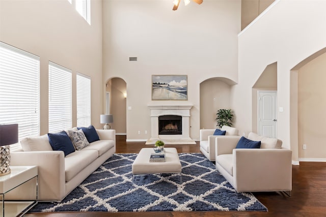 living room with dark hardwood / wood-style flooring, a high ceiling, and ceiling fan