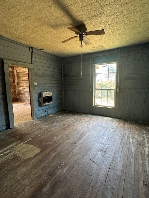 empty room featuring wood walls, ceiling fan, and hardwood / wood-style floors