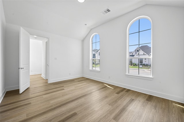 empty room with light hardwood / wood-style flooring, lofted ceiling, and a healthy amount of sunlight