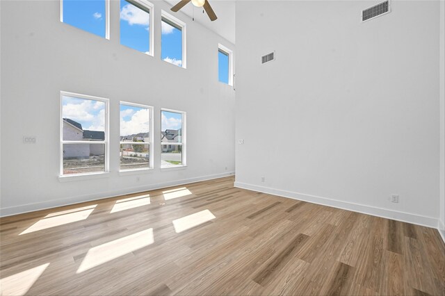 unfurnished living room featuring a high ceiling, light hardwood / wood-style floors, and ceiling fan