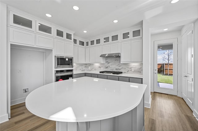 kitchen featuring stainless steel appliances, a center island, decorative backsplash, and white cabinetry