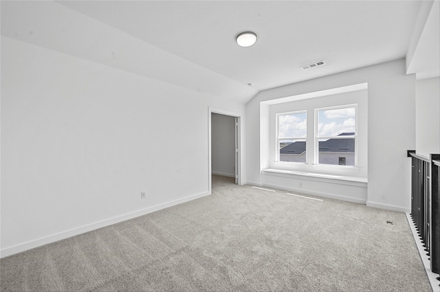 carpeted empty room with vaulted ceiling