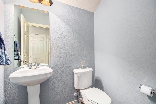 bathroom featuring a textured wall and toilet