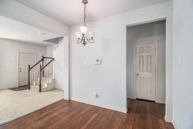 spare room with a notable chandelier and dark hardwood / wood-style floors