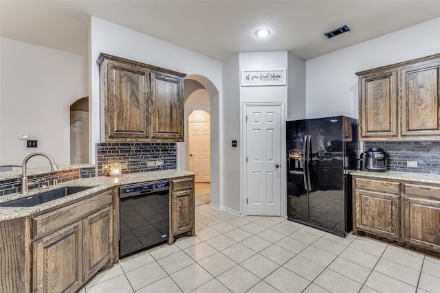 kitchen with light stone countertops, sink, backsplash, light tile patterned floors, and black appliances