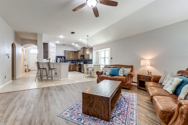 living room with ceiling fan, light hardwood / wood-style flooring, and vaulted ceiling