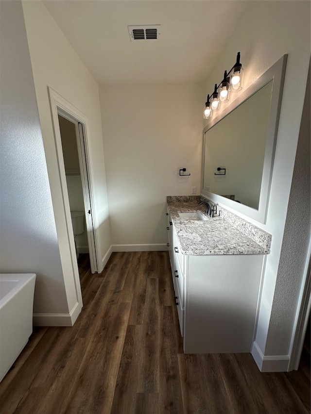 bathroom with hardwood / wood-style flooring, vanity, and toilet