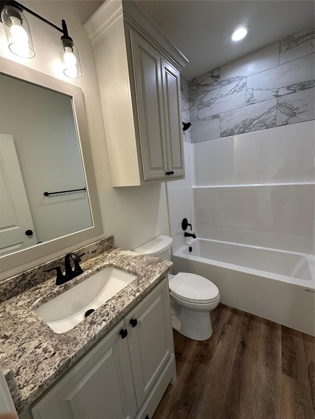 full bathroom with vanity, wood-type flooring, tiled shower / bath combo, and toilet