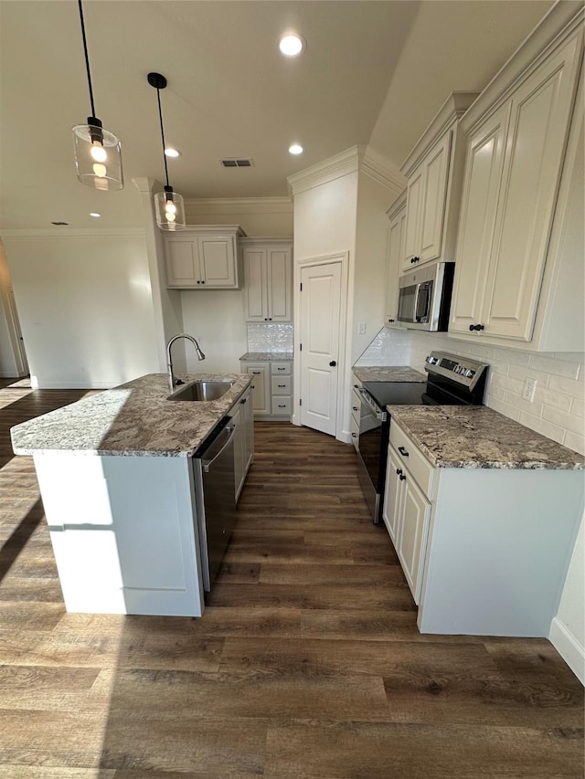 kitchen featuring pendant lighting, backsplash, sink, an island with sink, and appliances with stainless steel finishes