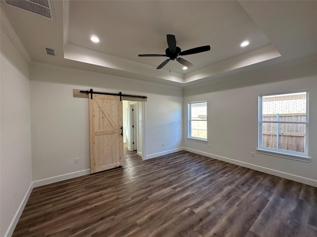 empty room featuring dark hardwood / wood-style flooring, a barn door, and a raised ceiling