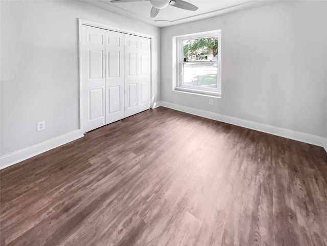 unfurnished bedroom with dark wood-type flooring, a closet, and ceiling fan