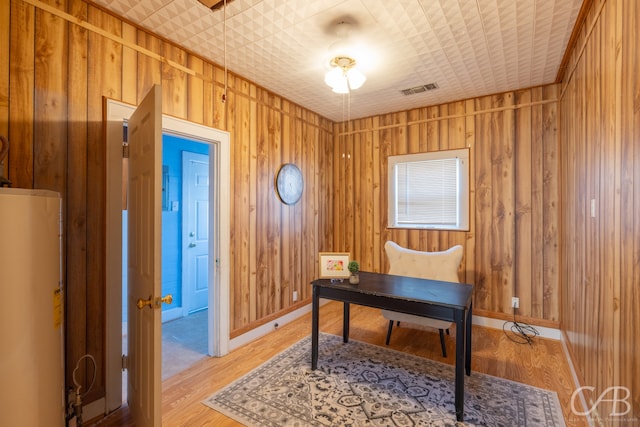 office area with wood walls, water heater, and hardwood / wood-style flooring