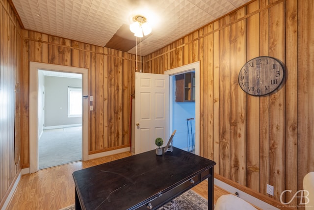 office space with light hardwood / wood-style flooring and wooden walls