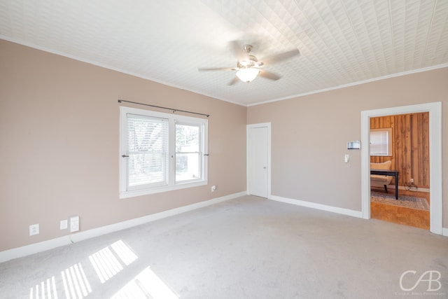 empty room with ornamental molding, carpet, and ceiling fan