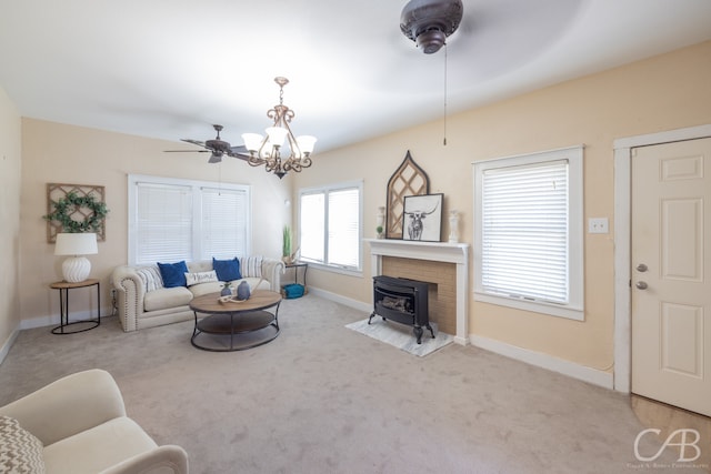 living room with light colored carpet, ceiling fan with notable chandelier, and a wood stove