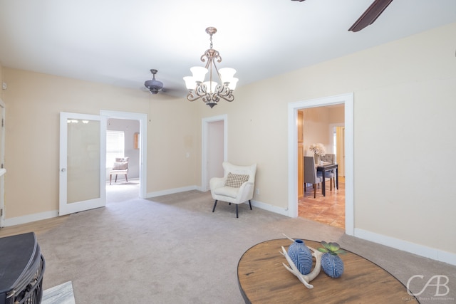 sitting room featuring ceiling fan with notable chandelier and light carpet