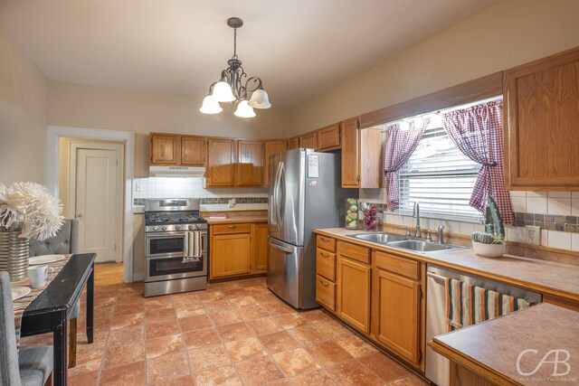 kitchen with a chandelier, tasteful backsplash, sink, hanging light fixtures, and appliances with stainless steel finishes