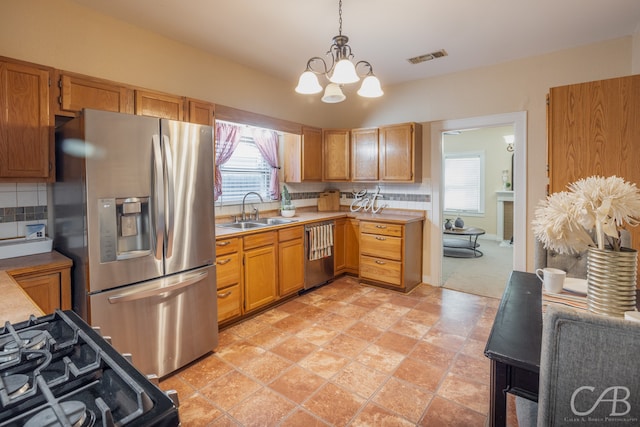 kitchen with decorative backsplash, sink, a notable chandelier, hanging light fixtures, and appliances with stainless steel finishes