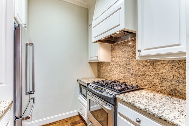 kitchen featuring white cabinetry, tasteful backsplash, light wood-type flooring, light stone counters, and appliances with stainless steel finishes