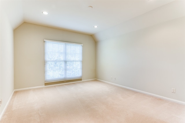 carpeted spare room featuring vaulted ceiling