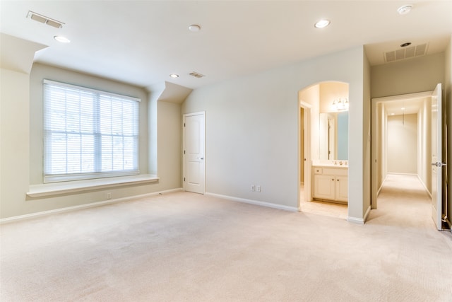 unfurnished bedroom with ensuite bath and light colored carpet