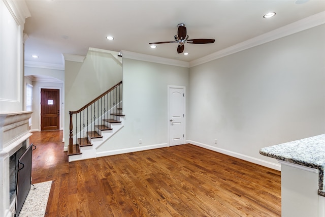 unfurnished living room featuring hardwood / wood-style flooring, crown molding, and ceiling fan