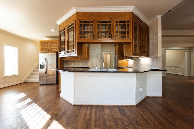 kitchen featuring dark wood-type flooring, tasteful backsplash, kitchen peninsula, and stainless steel fridge with ice dispenser