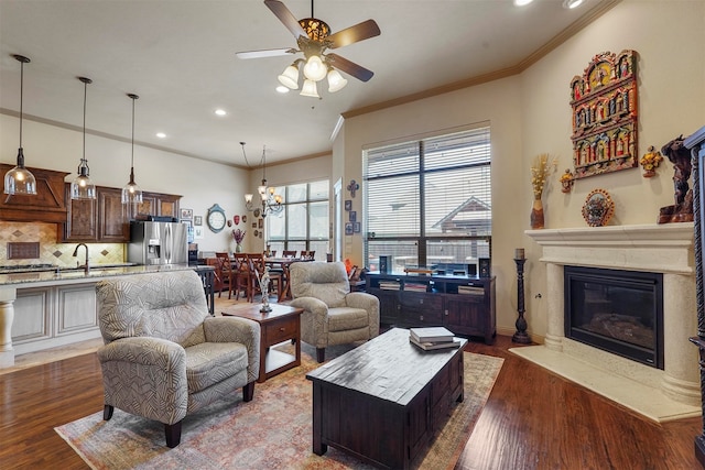 living room featuring ornamental molding, sink, ceiling fan with notable chandelier, and hardwood / wood-style floors