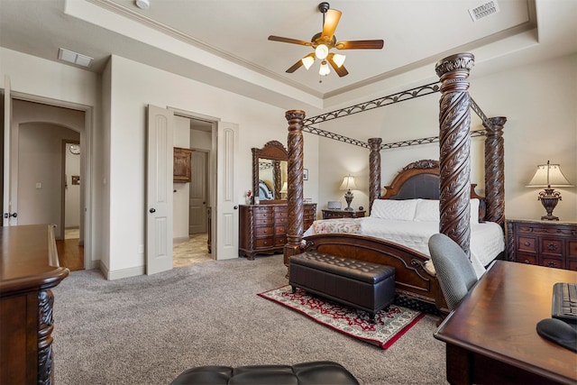 carpeted bedroom with ornamental molding, ceiling fan, and a raised ceiling