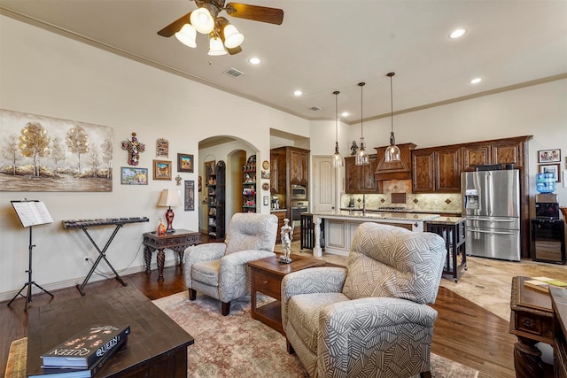 living room featuring crown molding, sink, light wood-type flooring, and ceiling fan