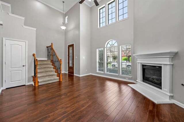 unfurnished living room featuring ceiling fan, wood-type flooring, and a high ceiling