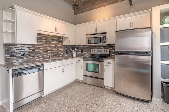 kitchen with white cabinets, stainless steel appliances, backsplash, and dark stone countertops