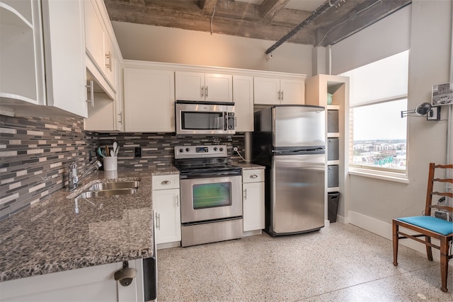 kitchen with white cabinetry, dark stone counters, stainless steel appliances, decorative backsplash, and sink