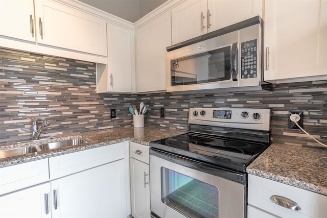 kitchen featuring dark stone counters, white cabinetry, sink, appliances with stainless steel finishes, and backsplash