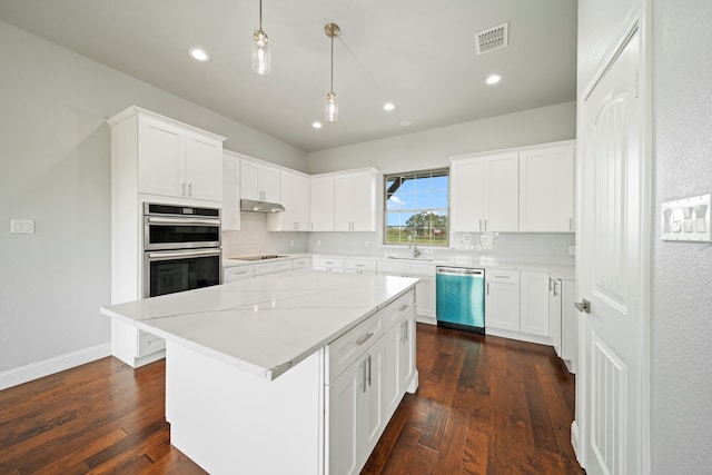 kitchen with dark wood-type flooring, appliances with stainless steel finishes, white cabinetry, and a kitchen island