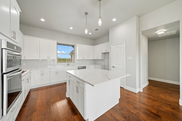 kitchen with white cabinetry, light stone countertops, dark wood-type flooring, a center island, and stainless steel double oven