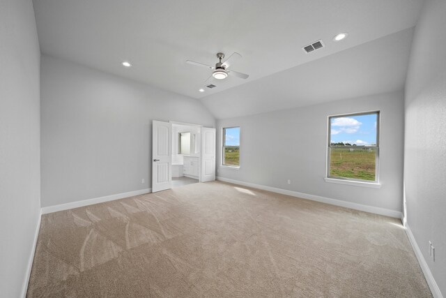 unfurnished bedroom with ensuite bath, vaulted ceiling, light carpet, and ceiling fan