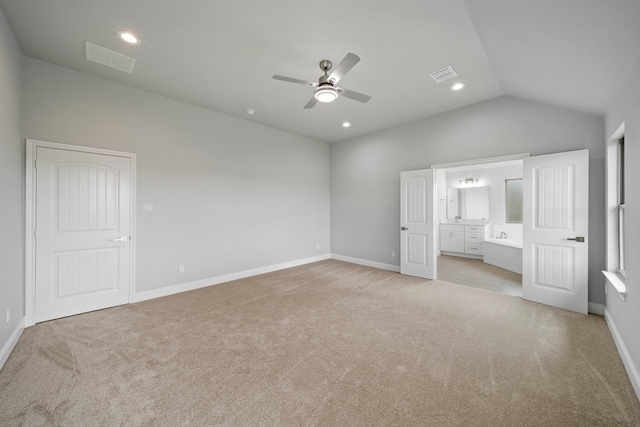 unfurnished bedroom featuring lofted ceiling, light carpet, ensuite bathroom, and ceiling fan