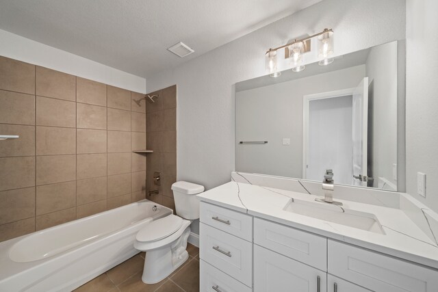 full bathroom featuring toilet, tile patterned flooring, tiled shower / bath combo, vanity, and a textured ceiling