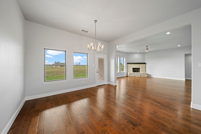 unfurnished living room featuring ceiling fan with notable chandelier, a fireplace, and dark hardwood / wood-style flooring